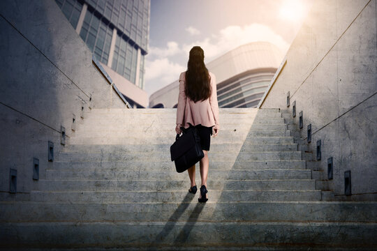 Rear view of businesswoman walking upward on stairs