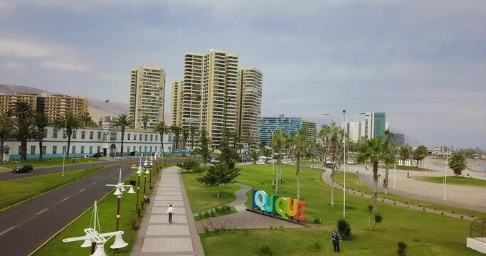 Man walking next a big sign of Iquique.