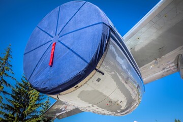 Closeup of covered with blue fabric turbine of an airplane against serene sky at the day of air forces.