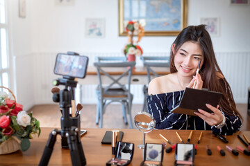 Young asian woman blogger recording video makeup cosmetic at home. Selling products online concept.