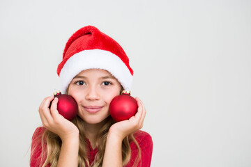 Young girl in red santa hat with christmas balls. Child with Christmas decoration, banner copy space. Isolated on white background.