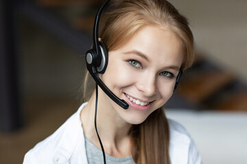 Smiling young close-up woman with headset and microphone looking at the camera.
