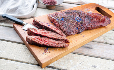 Gegrilltes Wagyu Bavette Steak vom Rind mit Rotwein Salz angeboten als close-up auf einem Modern Design Holz Board