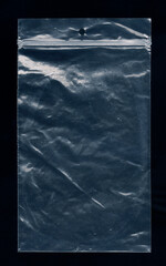 A transparent little plastic bag, used for shipping or storage of small items, isolated on a black surface. An empty canvas for your own writings or drawings.
