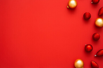 Top view of gold and red christmas ornaments in different shapes on the red background with place for text. New year flat lay.