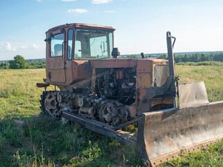 Old rusty tractor on tracks. Old farm equipment