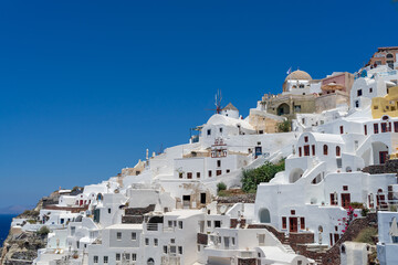 Fototapeta premium Panoramic view of Oia town in Santorini island with old whitewashed houses and traditional windmill, Greece Greek landscape on a sunny day