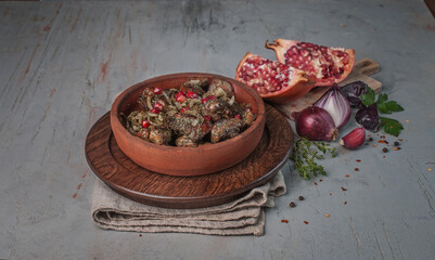 food photography of a traditional Georgian cuisine of  braised meat and pomegranate with herbs and spices close-up, in a brown ceramic bowl, side view, on a gray textured background