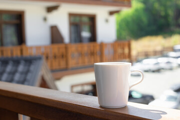 white mug with hot drink on a wooden terrace and green nature in the background. relax concept. close-up. soft focus