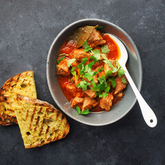 Slow cooked pork with vegetables, carrots, onions and ripe tomatoes with sweet peas and bay leaves in a plate. View from above. Comfortable homemade food.