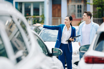 Female manager helping client to choose car in rental service parking