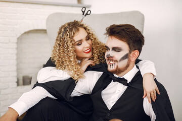 Couple at home. Woman wearing black costume. Lady with halloween makeup.