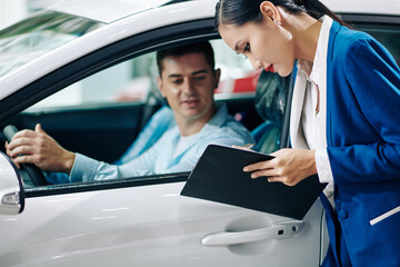 Car dealership manager filling customer details in document before test drive