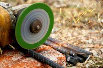 Obraz premium man is cutting iron road with help of iron cutter machine with golden sparkling come out of it