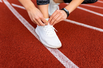 Female runner tying shoelaces on the running track