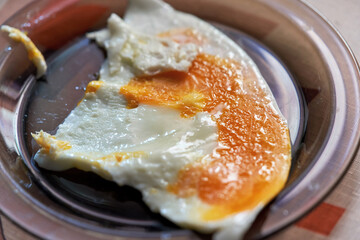 Fried egg with caked yolk in a transparent plate