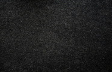 Black grainy asphalt background. Anti-slip road surface. Small items. Free space for text.