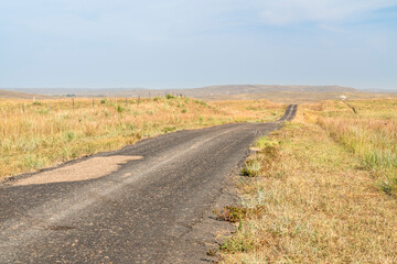 Fototapeta na wymiar narrow and rough rural highway in Nebraska Sandhills, midday hazy scenery affected by wildfire smoke from Colorado and Wyoming