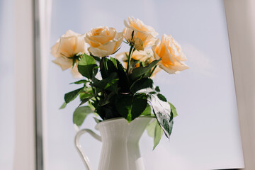 Bouquet of tea roses in white vase. Light background 