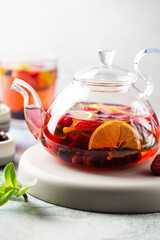 Fruit red tea with berries in glass teapot on white background