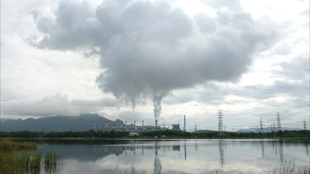 The atmosphere is tainted by air pollution as smoke and smog envelop the landscape, emanating from industrial activities, particularly a coal power plant