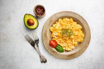 Fresh cooked scrambled eggs in a plate on white background, top view
