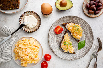 Scrambled egg sandwich with cream cheese on rye toast for breakfast on white background, top view. Healthy breakfast or snack