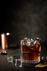 Glass of cold cola with ice cubes on dark background
