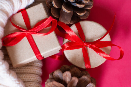 Christmas gifts from a round and square box, tied with a red ribbon on a red background with wooden cones. The view from the top. Space for text. A soft picture