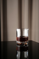 A glass of whiskey on a black piano
