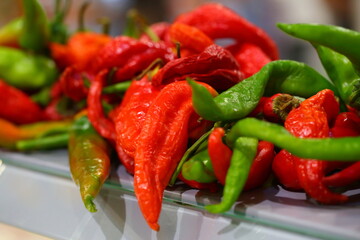 A bunch of hot peppers on a counter in a store on the street
