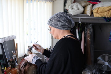 Middle aged woman receiving cancer treatment coloring wig in bedroom.
