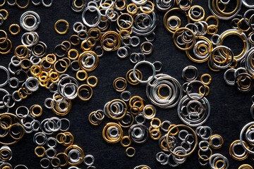 round metal links, accessories for jewelry making, scattered on a black background