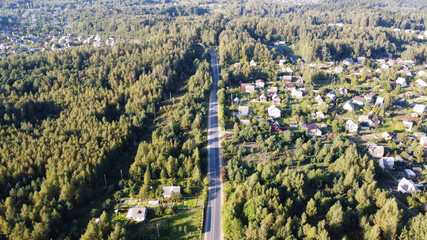 Top view of the highway near houses of a rural suburb on a sunny day