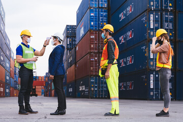 Worker scanning fever temperature with digital thermometer to construction site staff wearing...