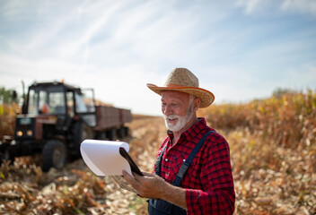 Portrait of senior farmer in front of tractor during corn harvest