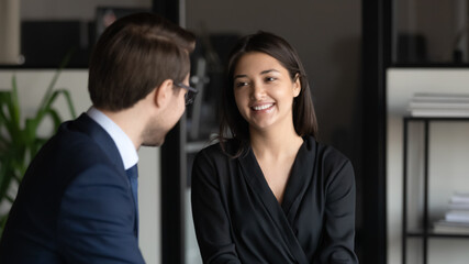 Head shot smiling young beautiful indian ethnicity female employee enjoying pleasant conversation with confident male leader in formal wear or discussing working issues with hr manager in office..