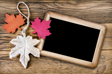 Autumn leaves and chalk board against wooden background