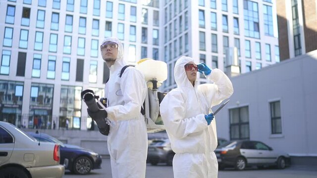 Professional cleaning and disinfection of the territory in the city due to the emergence of Covid-19 virus. Specialized friendly team in protective suits clean surface with equipment. - Powered by Adobe