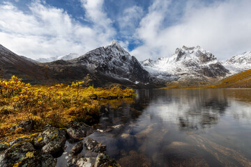 Fototapeta na wymiar Beautiful View of Scenic Alpine Lake, Rocks and Snowy Mountain Peaks in Canadian Nature. Season change from Fall to Winter. Taken at Grizzly Lake in Tombstone Territorial Park, Yukon, Canada.