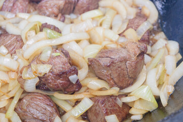 Cooking pilaf in a cauldron on the grill outside in the summer