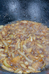 Cooking pilaf in a cauldron on the grill outside in the summer