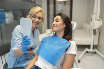 Female dentist in dental clinic providing examination and treatment of oral cavity for female...
