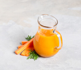 Vegetable drink carrot smoothie in a glass jug on a light gray background