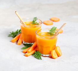Vegetable drink carrot smoothie in a glass with a bamboo straw on a light gray background