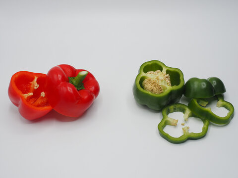 red bell pepper and green bell pepper devided into two piles on white background