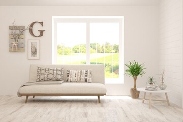 Fototapeta premium White living room with sofa and summer landscape in window. Scandinavian interior design. 3D illustration