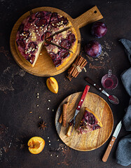 Homemade sweet plum pie or cake with nuts and spices on wooden board, dark brown stone background. Fruit pie. Rustic style.