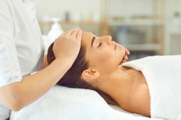 Fototapeta na wymiar Cosmetologist making manual rejuvenating facial massage for young woman in beauty salon