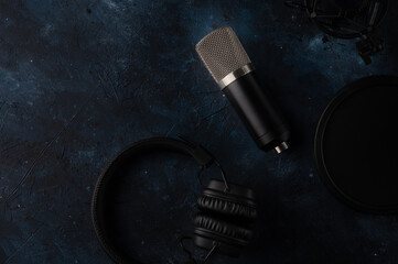 Headphone and studio microphone with shock mount and pop filter on dark blue background. Music...